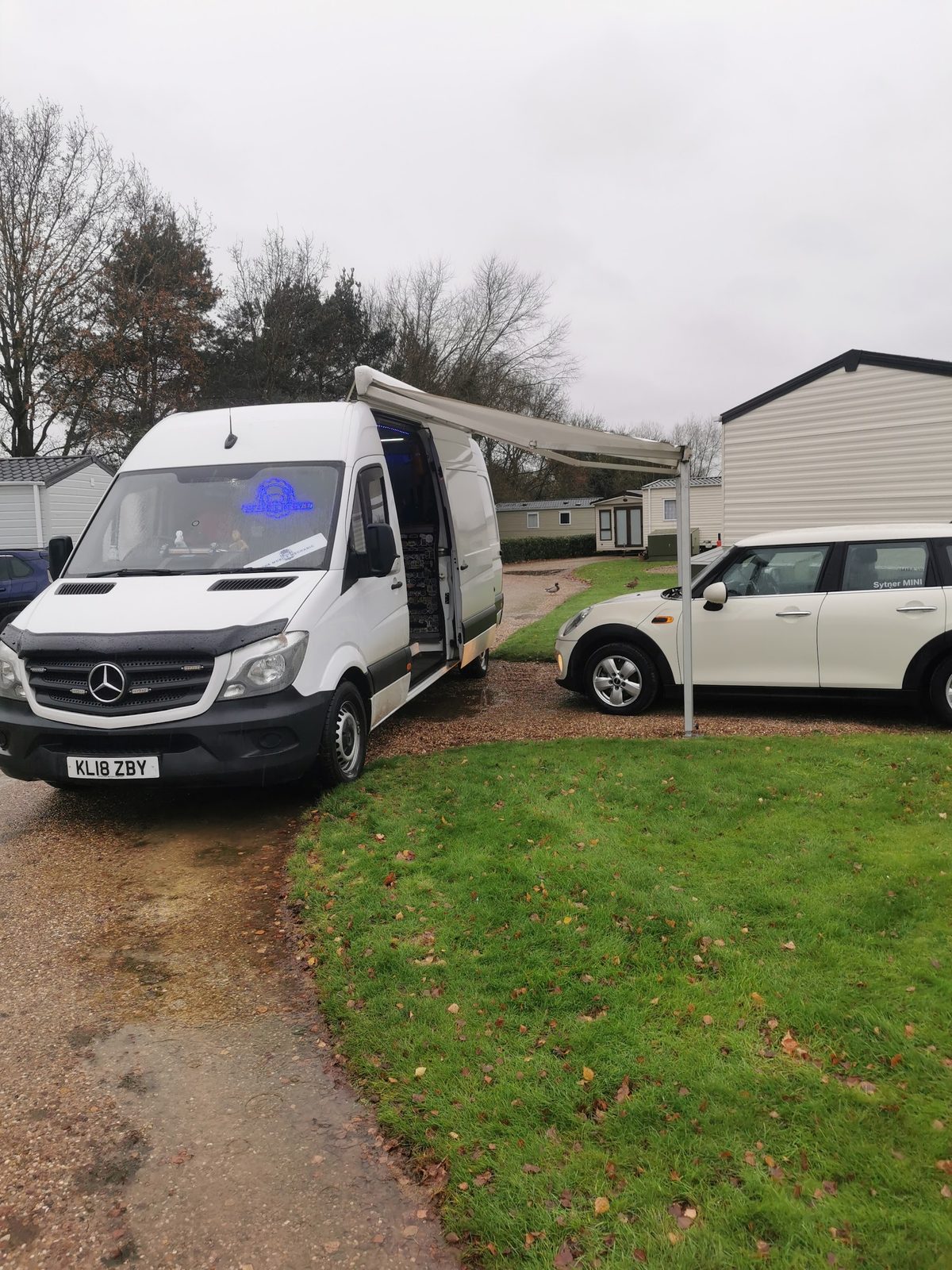 The Mobile Mechanic's white Mercedes Sprinter van with its awning out, parked on a driveway