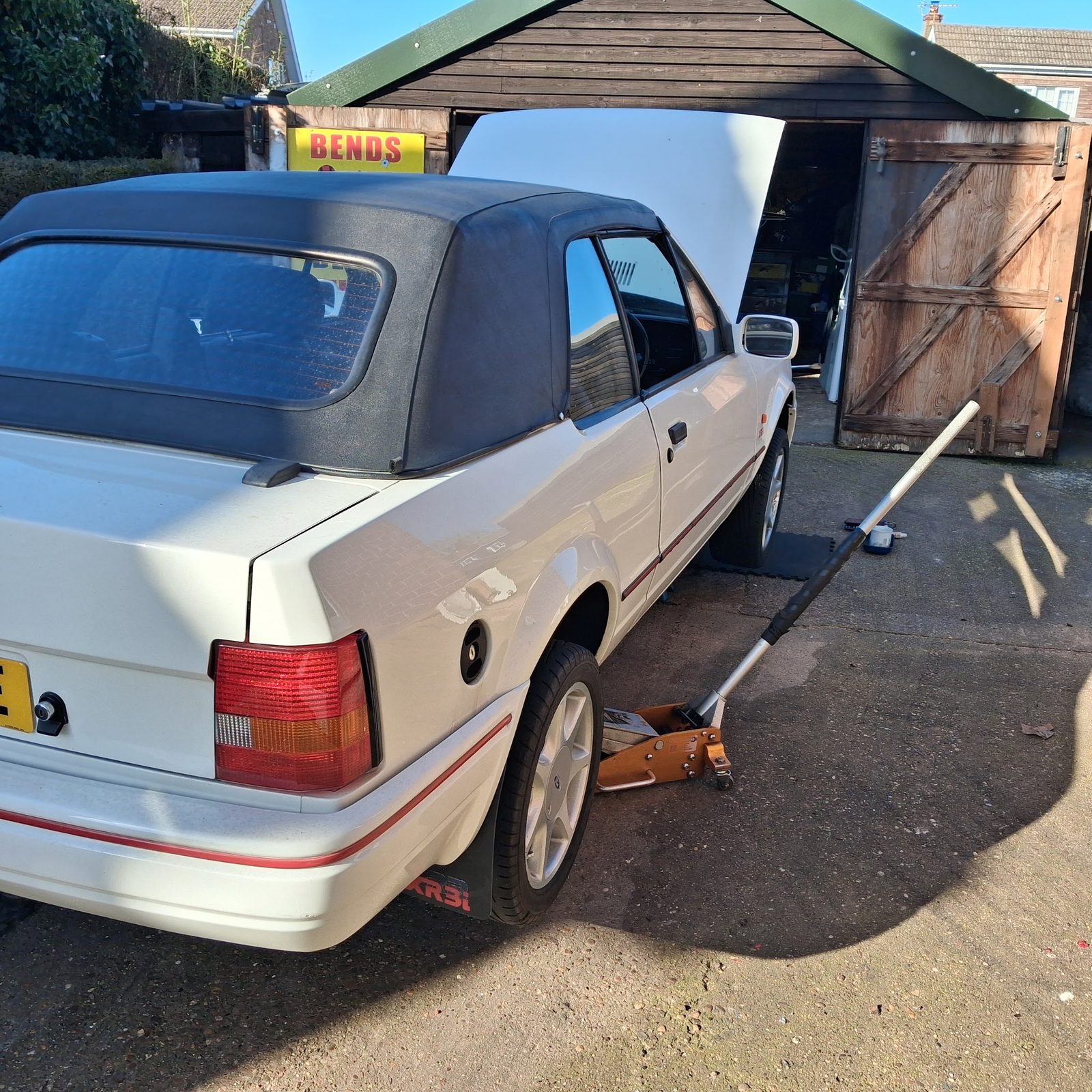 Rear three-quarter view of the white Escort XR3i on a jack